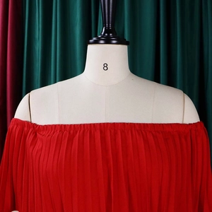 Détail de la robe rouge à épaules dénudées avec plis fins en mousseline et encolure élastique