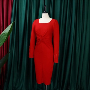 Détail d'une robe rouge à manches longues avec poignets perlés et taille torsadée