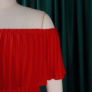Détail de la texture plissée de la robe rouge à épaules dénudées avec col élastique