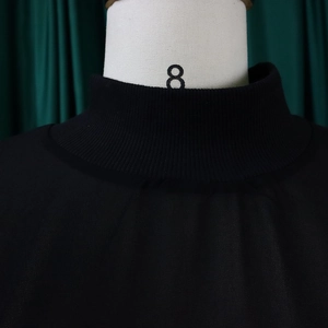 Macro-opname van zwarte mock neck jurk met geribbelde details bij de halslijn