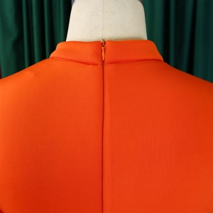 Close-up of orange dress featuring high collar and hidden zipper on back line