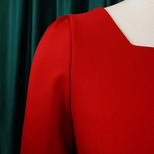 Détail de l'encolure carrée et des manches bouffantes sur cette robe rouge texturée