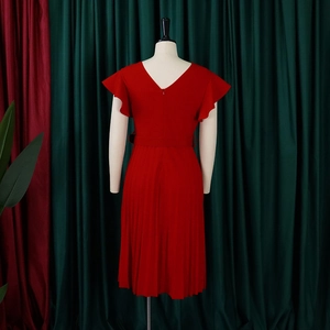 Detail of red summer dress with pleated hem, ruffled sleeves and matching belt on mannequin