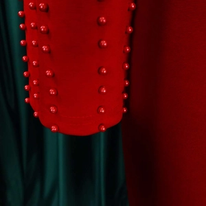 Gros plan sur la texture perlée rouge de la robe avec des perles assorties