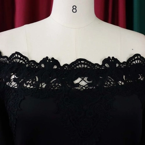 Close-up of elegant floral lace stitching on black off-shoulder cocktail dress neckline