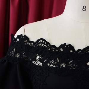 Detailaufnahme des schulterfreien Ausschnitts mit schwarzer Spitzenverzierung am Kleid