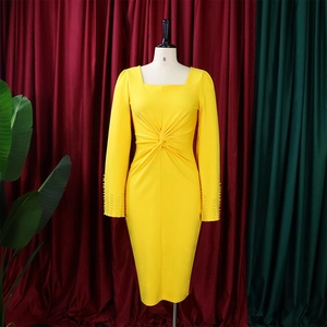 Détail de la robe fourreau jaune avec taille nouée et poignets perlés sur manches longues