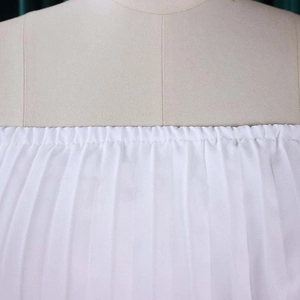 Détail du tissu en mousseline plissée blanche avec encolure élastique à épaules dénudées