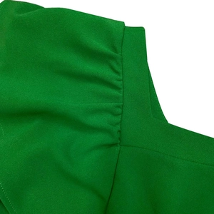 Detailed view of green ruffle shoulder seam and high-density crepe fabric texture
