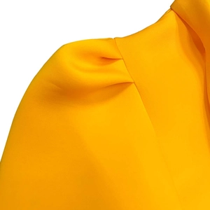 Detail of puff sleeves and pleated shoulder texture on a bright yellow summer dress