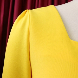 Détail de la robe jaune vif à col en V avec manches bouffantes plissées et tissu texturé