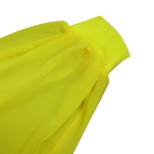 Detail van heldergele chiffon jurk met hoogelastische geribbelde manchetten en transparante stof