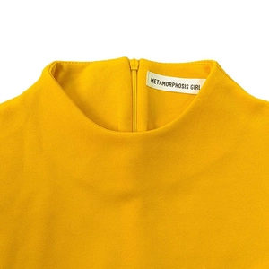 Détail du col rond et de la fermeture éclair sur une robe plissée jaune vif