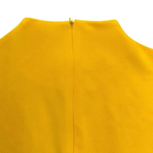 Vue macro de la fermeture éclair invisible sur une robe plissée jaune en tissu tissé