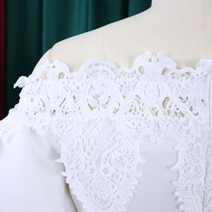 Detail of off-the-shoulder neckline featuring white floral lace and lantern sleeve craftsmanship