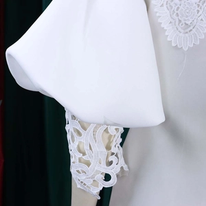 Detail of white puff sleeves featuring intricate embroidered lace and premium fabric texture