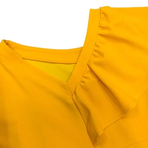 Detail of V-neckline with ruffled edge and textured fabric on bright yellow summer dress