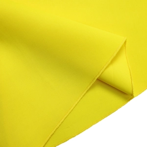 Macro shot of yellow dress fabric showing fine knitted texture and neat edge stitching