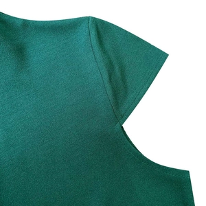 Détail de couture sur manche courte vert foncé et texture plissée de la robe