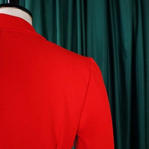 Detailansicht der strukturierten Schulter und des Revers eines roten eleganten Blazer-Kleides