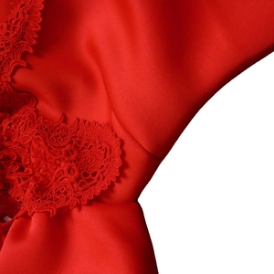 Makro-Detail der eleganten roten Spitze und des glatten Satinstoffs am Abendkleid