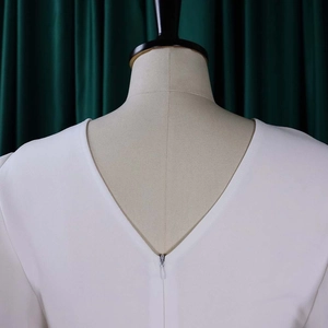 Detailed back view of white summer dress featuring deep V-neck and invisible zipper closure