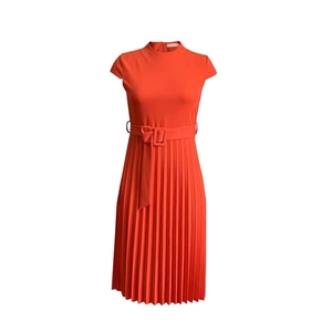 Détail de la taille nouée et du plissé fin sur une robe d'été de couleur rouge-orangé