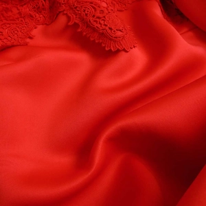 Detail of red satin fabric with luxury lace embroidery and smooth glossy finish