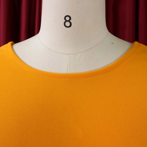 Detail of round neckline and textured fabric on vibrant orange summer dress