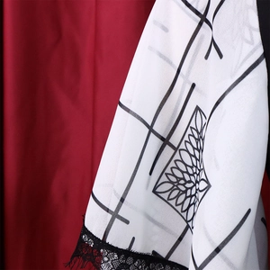 Detail of white dress with black floral patterns and delicate black eyelash lace trim