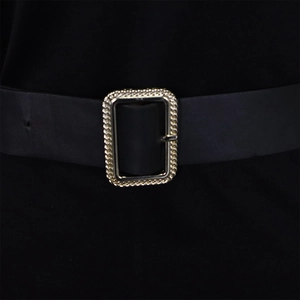 Detail of a black belt featuring a silver rectangular buckle with textured patterns