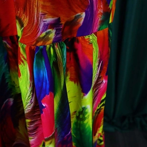 Macro detail of vibrant abstract floral print dress with intricate pleated fabric texture