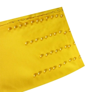Détail de tissu jaune avec cinq rangées de perles dorées et coutures précises