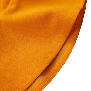 Detail of curved hem stitching and textured fabric on orange pleated summer dress