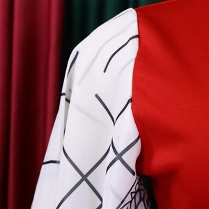Detail of red knit shoulder seams with white patterned geometric sleeves on a dress