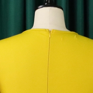 Close-up of the invisible zipper back on a yellow V-neck dress with bell sleeves
