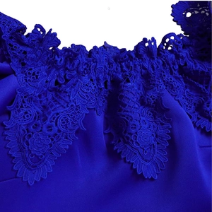 Detail of royal blue dress showing intricate floral lace embroidery and smooth fabric
