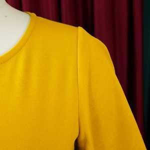 Detailed close-up of a vibrant yellow round-neck dress with textured fabric stitching