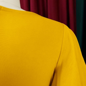 Detailed view of yellow dress shoulder showing heavy twill fabric and ruffle sleeve seam