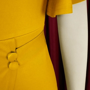 Close-up of mustard yellow dress featuring textured fabric and cloth-covered buttons