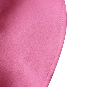 Macro detail of pink pleated fabric showing fine woven texture and neat stitching on dress edge