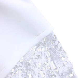 Close-up of intricate white lace embroidery and fine woven fabric on the dress sleeve hem