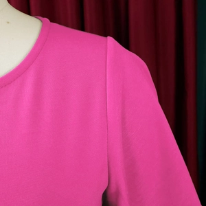 Detail shot of rose red high-waisted dress showing round neckline and fine fabric texture