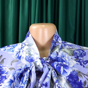 Dettaglio di camicetta in raso a fiori con elegante fiocco sullo scollo su un manichino