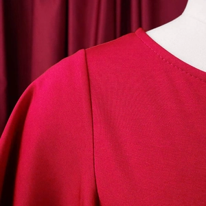 Close-up of red high waist dress showing honeycomb knit texture and ruffle sleeve seam