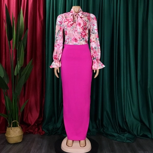Dettaglio della camicia a fiori con fiocco e gonna lunga a vita alta color magenta