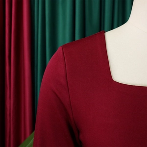 Detalle del vestido rojo oscuro mostrando el escote cuadrado y el tejido texturizado en maniquí