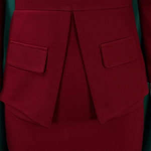 Detalle del vestido rojo oscuro con pliegues estructurales y bolsillos peplum en cintura