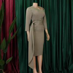 Detail of olive green dress featuring asymmetric neckline and elegant waist pleats