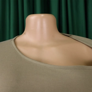 Detail view of olive green dress featuring asymmetrical neckline and premium fabric texture